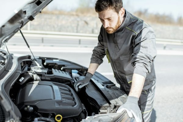 Auto mechanic repairing car outdoors